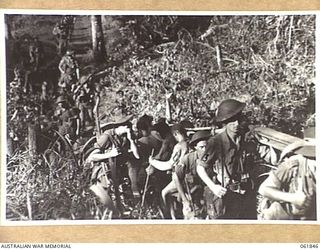 UBERI, NEW GUINEA. 1943-12-19. MEN OF THE 2/9TH AUSTRALIAN INFANTRY BATTALION AND NATIVE CARRIERS ACTING AS EXTRAS ON THE KOKODA TRAIL IN THE OWEN STANLEY RANGES DURING THE FILMING OF "RATS OF ..