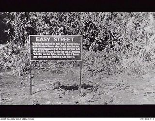 FINSCHHAFEN, NEW GUINEA. 1944-01. SIGN ERECTED BY MEMBERS OF THE 9TH DIVISION, RECORDING THE TAKING OF THE EASY STREET SUPPLY LINE. `EASY STREET. 2/17TH BN (LESS TWO COYS) TOOK THIS ROUTE, THEN A ..