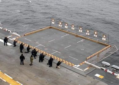 A high-angle view showing US Navy (USN) Sailors engage in a live fire weapons qualification using 5.56 mm M16A2 rifles, on the flight deck of the USN Tarawa Class Amphibious Assault Ship, USS SAIPAN (LHA 2), while the ship is underway in the Atlantic Ocean, conducting routine operations