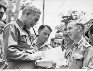 LAE, NEW GUINEA, 1945-12-25. THE RIGHT HONOURABLE J. B. CHIFLEY, PRIME MINISTER OF AUSTRALIA (1) SIGNING AUTOGRAPH BOOKS FOR MEMBERS OF NO 2 OTHER RANKS' MESS FIRST ARMY, DURING HIS VISIT TO THE ..