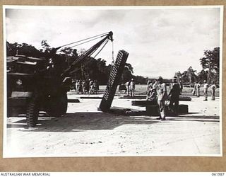 DREGER HARBOUR, NEW GUINEA. 1943-12-03. PORTABLE CRANE TRUCK OF THE 870TH UNITED STATES AVIATION ENGINEER BATTALION PICKING UP A BUNDLE OF STEEL MATTING TO BE USED FOR THE CONSTRUCTION OF A NEW ..