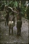 Pig festival: boy annointed with bespelled water from bamboo tube held by elder