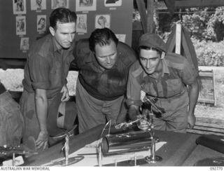 JACQUINOT BAY, NEW BRITAIN. 1945-06-06. PRIVATE J. GROTH, 2/1 GUARD REGIMENT (1), PRIVATE F.J. MCGILL, 4 FIELD AMBULANCE (2) AND DRIVER F.M. BOSAID, 4 FIELD AMBULANCE (3), ADMIRE A DINNER-GONG ..