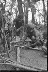 Pig festival, stake-planting, Tuguma: man applies substance from small packet to sharpened stake