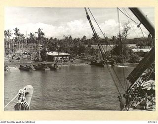 MADANG, NEW GUINEA. 1944-05-12. THE VIEW FROM AN AMERICAN MERCHANT "LIBERTY" SHIP LOOKING TOWARDS THE LANDING BEACH AND BATTERED HOUSES. THE VESSEL'S DERRICK SWINGS AT THE UPPER RIGHT FOREGROUND ..