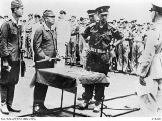 GENERAL IMAMURA PRESENTS HIS SWORD TO GENERAL STURDEE ON THE FLIGHT DECK OF HMS GLORY DURING THE SURRENDER CEREMONY OF THE JAPANESE FORCES AT RABAUL, 1945-09-06