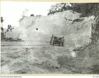 LANGEMAK BAY, NEW GUINEA, 1944-03-20. THIS CUT ON MARSH ROAD MADE BY C COMPANY, 870TH UNITED STATES AVIATION ENGINEER BATTALION MEASURING 80 FEET DEEP, 60 FEET WIDE AND 200 YARDS LONG, ALLOWED THE ..