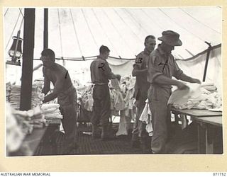 LAE, NEW GUINEA. 1944-03-25. MEMBERS OF THE 1ST MOBILE HOSPITAL LAUNDRY UNIT FOLDING WASHED AND DRIED CLOTHES IN THE DESPATCH BAY. LEFT TO RIGHT: NX177367 PRIVATE N. C. WATSON; N215394 PRIVATE A. ..