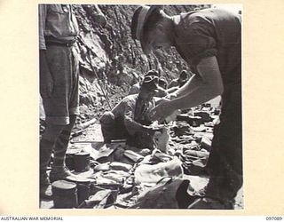 MOUNT SHIBURANGU, WEWAK AREA, NEW GUINEA. 1945-09-21. AUSTRALIAN SOLDIERS SEARCHING THE PERSONAL EQUIPMENT OF JAPANESE SOLDIERS OF 18 JAPANESE ARMY AT A CONTROLLING POINT AT MAKOW ON THE TOP OF ..