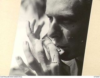 MILILAT, NEW GUINEA. 1944-08-23. VX147856 CORPORAL L. SMITH HARMONICA SOLOIST OF THE "TASMANIACS" THE TASMANIAN LINES OF COMMUNICATION CONCERT PARTY PRACTISING DURING A CONCERT REHEARSAL