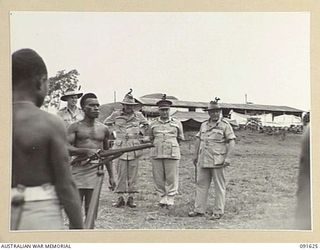 NADZAB, NEW GUINEA. 1945-05-11. GENERAL SIR THOMAS A. BLAMEY, COMMANDER-IN-CHIEF, ALLIED LAND FORCES, SOUTH WEST PACIFIC AREA (4), AND SENIOR OFFICERS WATCHING A NATIVE NON COMMISSIONED OFFICER OF ..