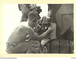 WANDOKAI, NEW GUINEA. 1944-04-22. AN AUSTRALIAN ARMY SIGNALLER USING A 108 MK II SET TO MAINTAIN COMMUNICATION WITH AN OBSERVATION POST FROM A LCM (LANDING CRAFT MECHANIZED) DURING LANDING TRIALS ..