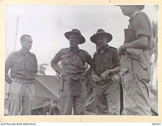 SUAIN PLANTATION, NEW GUINEA. 1944-12-10. MAJOR-GENERAL J.E.S. STEVENS, GENERAL OFFICER COMMANDING 6 DIVISION, (3), DISCUSSES WITH BRIGADIER J. REDDISH, (2), AND LIEUTENANT-COLONEL S.L. BLEBY, 2/3 ..