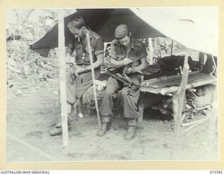 Karkar Island, Wewak Area, New Guinea. 1944-06-03. VX147237 Corporal A.R. McColl, on the left, and VX109275 Private N.H. Phillips, members of the 37/52nd Australian Infantry Battalion, cleaning ..