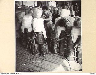 WEWAK AIRSTRIP, NEW GUINEA. 1945-08-06. TROOPS OF HEADQUARTERS COMMAND, AUSTRALIAN ARMY SERVICE CORPS, 6 DIVISION, AT AIR MAINTENANCE DEPOT ATTACHED TO THE DETAIL ISSUE DEPOT FASTENING PARACHUTES ..