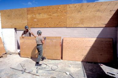 A member of a naval mobile construction battalion cuts wood with a reciprocating saw as his unit constructs a volleyball court