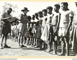 NEW GUINEA. 1942-08. SUPERFICIAL EXAMINATION OF NATIVE CARRIERS ON THE MORNING SICK PARADE BY THE REGIMENTAL AID POST ATTENDANT WARRANT OFFICER II. J.N. WALSHE. IN THESE DAYS WHEN LARGE NUMBERS OF ..