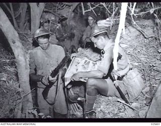 PORT MORESBY, PAPUA, 1942-07. AUSTRALIAN TROOPS MANNING POSTS IN THE NEW GUINEA BUSH RELAX FOR A FEW MOMENTS TO CLEAN A RIFLE AND SCAN A PICTORIAL MAGAZINE