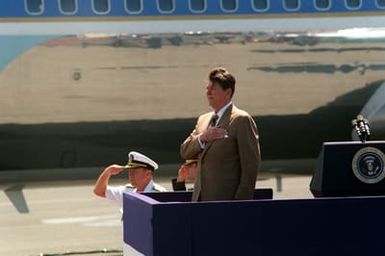 President Ronald Reagan stands at attention as the National Anthem is played upon his arrival aboard Air Force One. The president and first lady are visiting Hawaii while en route to the Republic of China