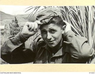 1943-07-14. NEW GUINEA. WAU-MUBO AREA. ALONG THE MUBO TRACK CPL. J.A. ROBERTSON, OF SURREY HILLS, VIC., WITH A HAT HE SOUVENIRED FROM A JAPANESE CAMP. CPL. ROBERTSON HAS OFTEN BEEN RIGHT INTO ..