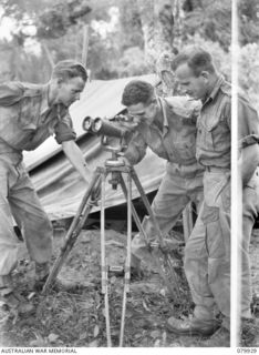 DAGUA, NEW GUINEA. 1945-03-25. MEMBERS OF "I" SECTION, 2/2 INFANTRY BATTALION EXAMINE A CAPTURED SET OF JAPANESE ANTI- AIRCRAFT BINOCULARS AT THE AIRSTRIP. IDENTIFIED PERSONNEL ARE:- NX72243 ..