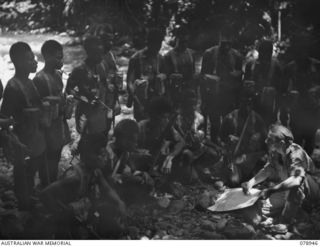 OIVA RIVER, NEW BRITAIN. 1945-02-07. NX166834 SERGEANT D.E. SLOAN B COMPANY, 1ST NEW GUINEA INFANTRY BATTALION GIVING INSTRUCTIONS TO A NATIVE PATROL BEFORE MOVING OUT FROM THE CAMP AREA