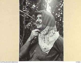 1943-09-14. NEW GUINEA. KOMIATUM RIDGE. CPL. FRANK YOUNG, OF PORT MORESBY USES A JAPANESE FLAG IN A MANNER WHICH ITS OWNER NEVER INTENDED. THE FLAG WAS FOUND AFTER THE JAPANESE HAD BEEN DRIVEN FROM ..