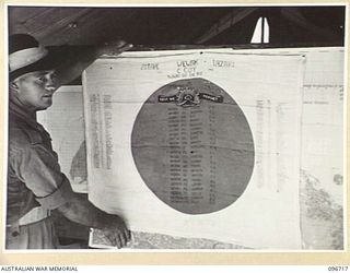 CAPE WOM, WEWAK AREA, NEW GUINEA, 1945-09-20. PRIVATE S. DAVIS, 2/4 INFANTRY BATTALION WITH HIS FAMOUS JAPANESE FLAG. IN THE RED SPOT, CENTRE OF FLAG, ARE THE NAMES OF MEMBERS OF C COMPANY, 2/4 ..