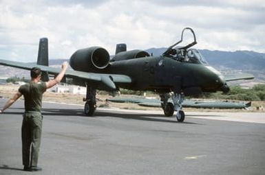 A ground crewman signals to an A-10A Thunderbolt II aircraft of the 18th Tactical Fighter Squadron, 343rd Tactical Fighter Wing, taxiing on the flight line during Exercise OPPORTUNE JOURNEY 85-3