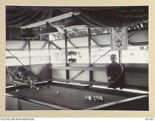 LAE, NEW GUINEA, 1945-05-09. PRIVATE M.C. MCNAMARA (1), AT THE TABLE AND SERGEANT C.A. CASEYZERK (2), WAITING HIS TURN TO PLAY IN THE BILLIARD ROOM AT 112 CONVALESCENT DEPOT