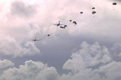 Several US Marines from 2nd Platoon, Company A, 5th Force Reconnaissance Battalion, 3rd Marine Division, glide down with the MC1-1 static line round parachutes over the drop zones after they jumped out of two US Air Force C-141 Starlifters, 800 feet above sea level, during Force Reconnaissance Exercises