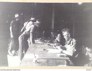 LAE, NEW GUINEA. 1944-08-16. TROOPS OF HEADQUARTERS, NEW GUINEA FORCE REGISTERING THEIR VOTE FOR THE AUSTRALIAN FEDERAL REFERENDUM AT THE UNIT PICTURE THEATRE. IDENTIFIED PERSONNEL ARE:- CAPTAIN ..