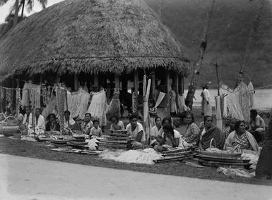 [Samoans displaying souvenirs in front of a Fale]