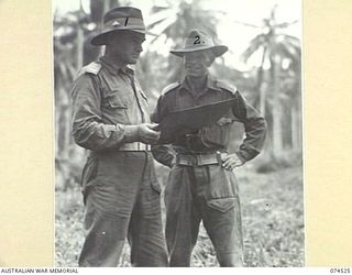 MADANG, NEW GUINEA. 1944-07-07. VX57 MAJOR A.K. CARROLL, SECOND IN CHARGE (1) AND VX185 LIEUTENANT-COLONEL G.F. SMITH, DSO, COMMANDING OFFICER, 24TH INFANTRY BRIGADE (2) DISCUSSING CAMP ..