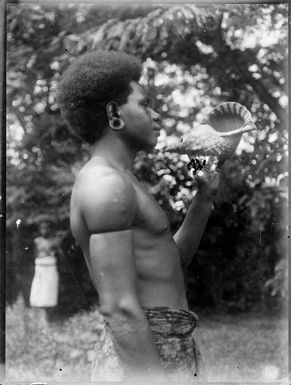 Man holding conch shell in Chinnery's garden, Malaguna Road, Rabaul, New Guinea, ca. 1935 / Sarah Chinnery