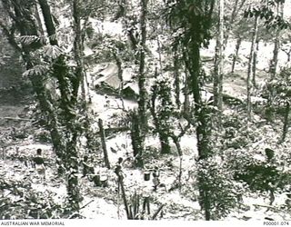 THE SOLOMON ISLANDS, 1945-03-27. GENERAL VIEW OF AN ALLIED CAMPSITE AND SOME NATIVE CARRIERS ON THE NUMA NUMA TRAIL ACROSS BOUGAINVILLE ISLAND. (RNZAF OFFICIAL PHOTOGRAPH.)