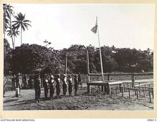 TALILI, NEW BRITAIN. 1945-10-12. JAPANESE SOLDIERS SALUTING THE AUSTRALIAN FLAG. MEMBERS OF 11 DIVISION ARE BESIDE THE ROAD BLOCK IN THE BACKGROUND, WHICH IS AT THE END OF THE AUSTRALIAN AREA ON ..