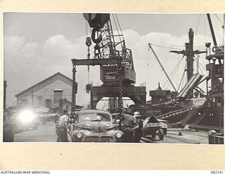 TOWNSVILLE, QLD. 1944-10-18. ELECTRIC CRANES LOADING STAFF CARS OF FIRST ARMY INTO HOLDS ABOARD THE LIBERTY SHIP SS JAMES OLIVER DURING EMBARKATION TO LAE, NEW GUINEA