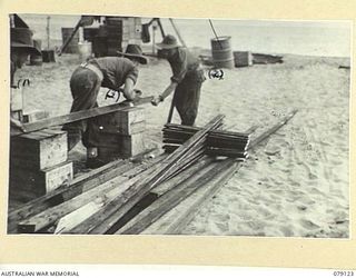 TSIMBA AREA, BOUGAINVILLE ISLAND. 1945-02-13. PRIVATE P. PHILLIPS (1) AND SERGEANT J. COLE (2) 31/51ST INFANTRY BATTALION MAKING WOODEN CROSSES ON THE BEACH AT PUTO