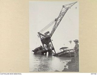 RABAUL, NEW BRITAIN. 1945-10-08. THE WRECKAGE OF A HUGE JAPANESE FLOATING CRANE ON THE SHORE OF BLANCHE BAY