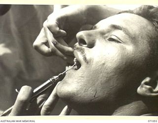 KILIGIA, NEW GUINEA. 1944-03-13. SX11107 CORPORAL K. MITTEN (1), OF THE 2/14TH FIELD REGIMENT, RECEIVING AN INJECTION PRIOR TO TREATMENT AT "E" SECTION, 2/5TH DENTAL UNIT. THE OBJECT OF THIS DENTAL ..