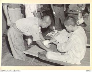 BOUGAINVILLE. 1945-09-28. A JAPANESE ORDERLY DRESSING THE WOUND OF A JAPANESE SOLDIER WOUNDED IN THE BOUGAINVILLE FIGHTING. SICK AND WOUNDED PATIENTS ARE BEING CARED FOR BY JAPANESE MEDICAL ..