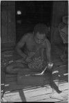 Canoe-building: man uses an adze to smooth small piece of wood for canoe part