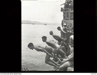 MILNE BAY, PAPUA. C.1944-02. AIRMEN FROM NO. 75 SQUADRON RAAF DIVING INTO MILNE BAY TO COOL OFF WITH A SWIM WHILE THEIR SHIP IS WAITING FOR CONVOY TO LAE. NOTE THE MAN WITH RIFLE IN TOP RIGHT HAND ..