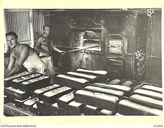 PORT MORESBY, NEW GUINEA. 1944-04-20. N163025 PRIVATE R. O'NEILL (1), AND NX149147 CORPORAL L.A. JOHNSTON (2), MEMBERS OF THE 6TH FIELD BAKING PLATOON LOAD AN OVEN WITH BREAD AT THE "STEAMSHIP ..