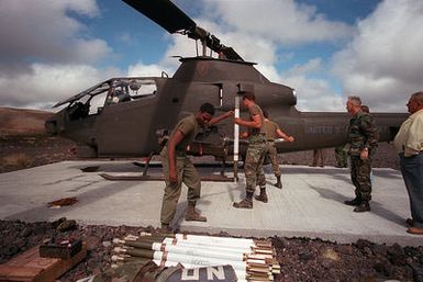 Ground crewmen of Delta Company, 25th Combat Aviation Battalion, 25th Inf. Div., load ammunition onto an AH-1 Huey cobra helicopter for live fire exercises being held at the Cobra Range