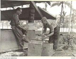 JACQUINOT BAY, NEW BRITAIN. 1945-02-04. NX103846 LIEUTENANT A.P. MORRIS (1) AND NX174918 SERGEANT R.F. MURRAY (2) ARMY AMENITIES SERVICE, 5TH BASE SUB AREA, CHECKING AND SORTING A NEW CONSIGNMENT ..