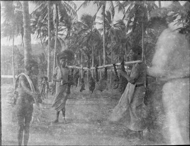 Two men carrying pieces of meat on a pole, Papua, ca. 1923 / Sarah Chinnery