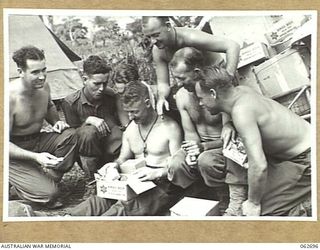 RAMU VALLEY, NEW GUINEA. 1943-12-22. MEN OF THE 2/31ST AUSTRALIAN INFANTRY BATTALION INVESTIGATE THE CONTENTS OF AN AUSTRALIAN COMFORTS FUND CHRISTMAS HAMPER