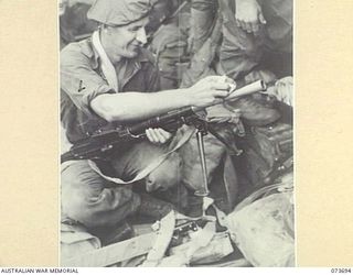 AT SEA, NEW GUINEA. 1944-06-01. QX138677 PRIVATE WALTER JULIUS KAHL, 37/52ND INFANTRY BATTALION, GIVES A LAST MINUTE CHECK AND CLEAN TO HIS BREN GUN BEFORE THE WEAPON IS USED IN THE ATTACK ON THE ..